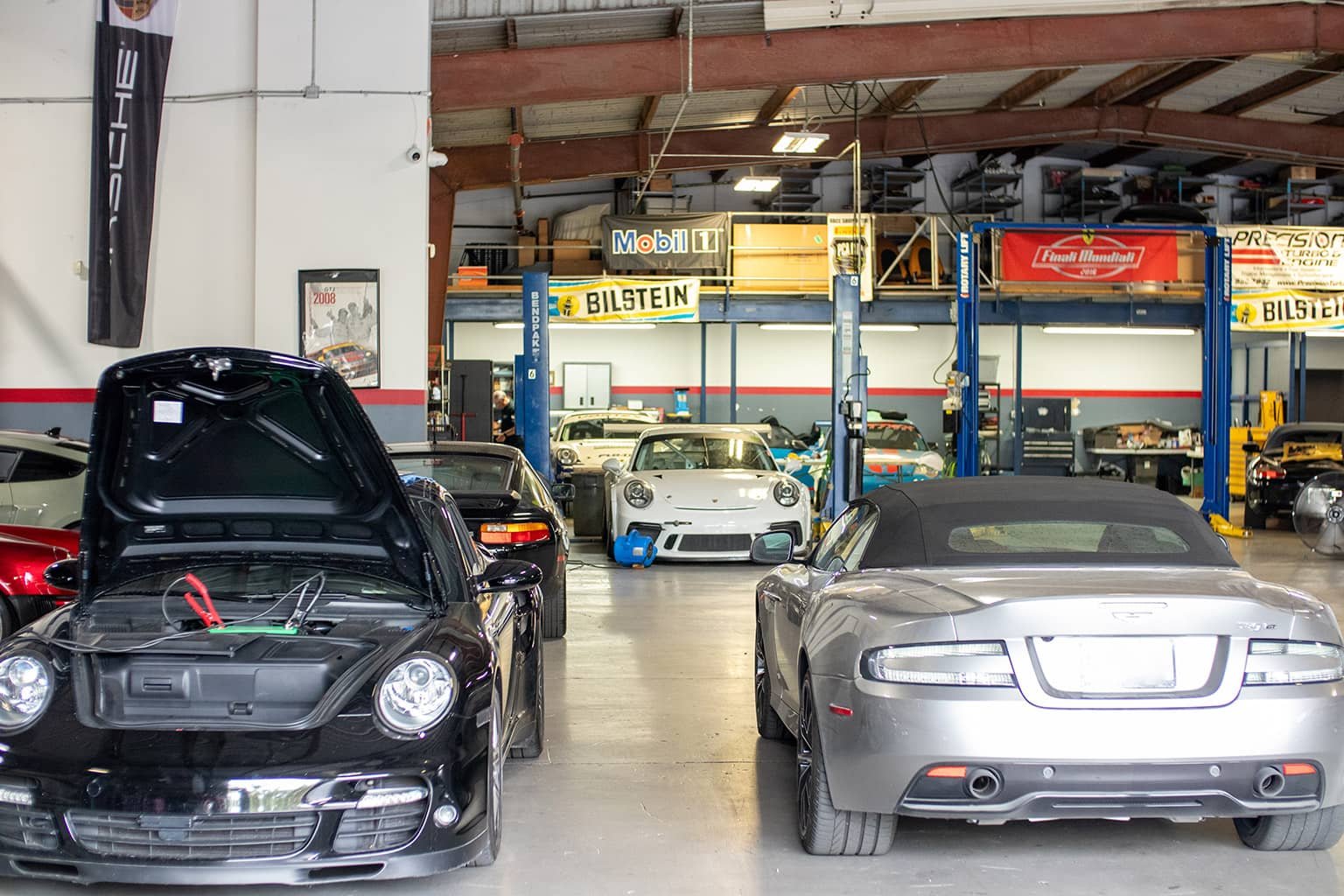 Porsche 911s and an Aston Martin inside the Vortex Motorsport service bays