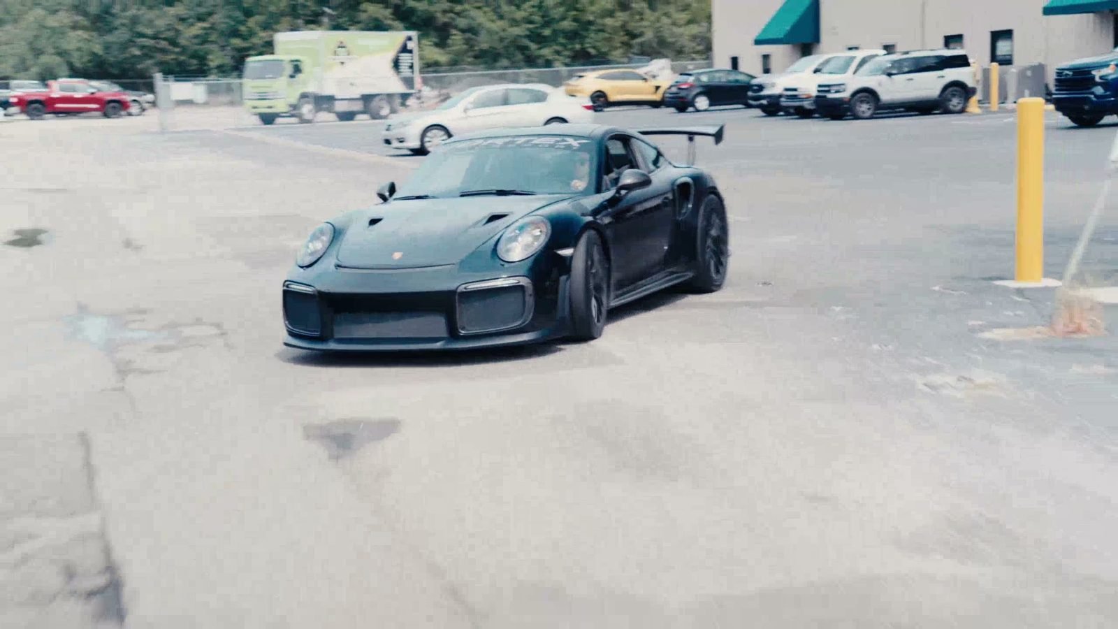 A Porsche GT2 RS with a Vortex Motorsport windshield banner leaving the shop